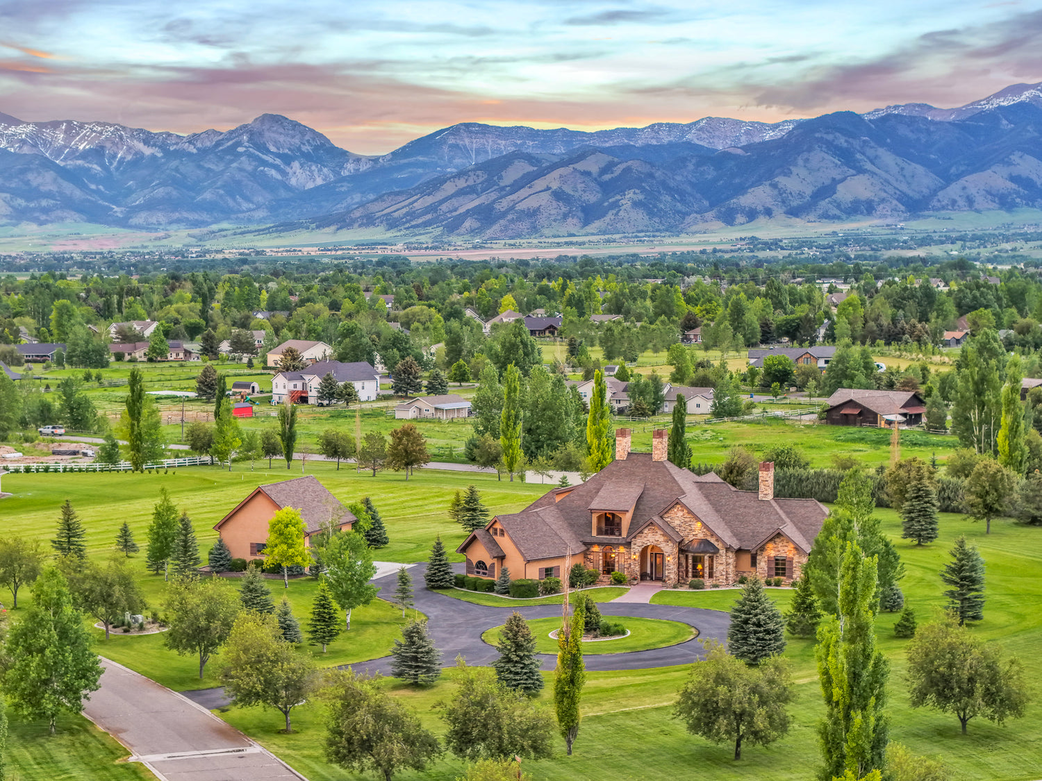Large stone home and detached garage with Bridger mountains at sunset in Bozeman, Montana