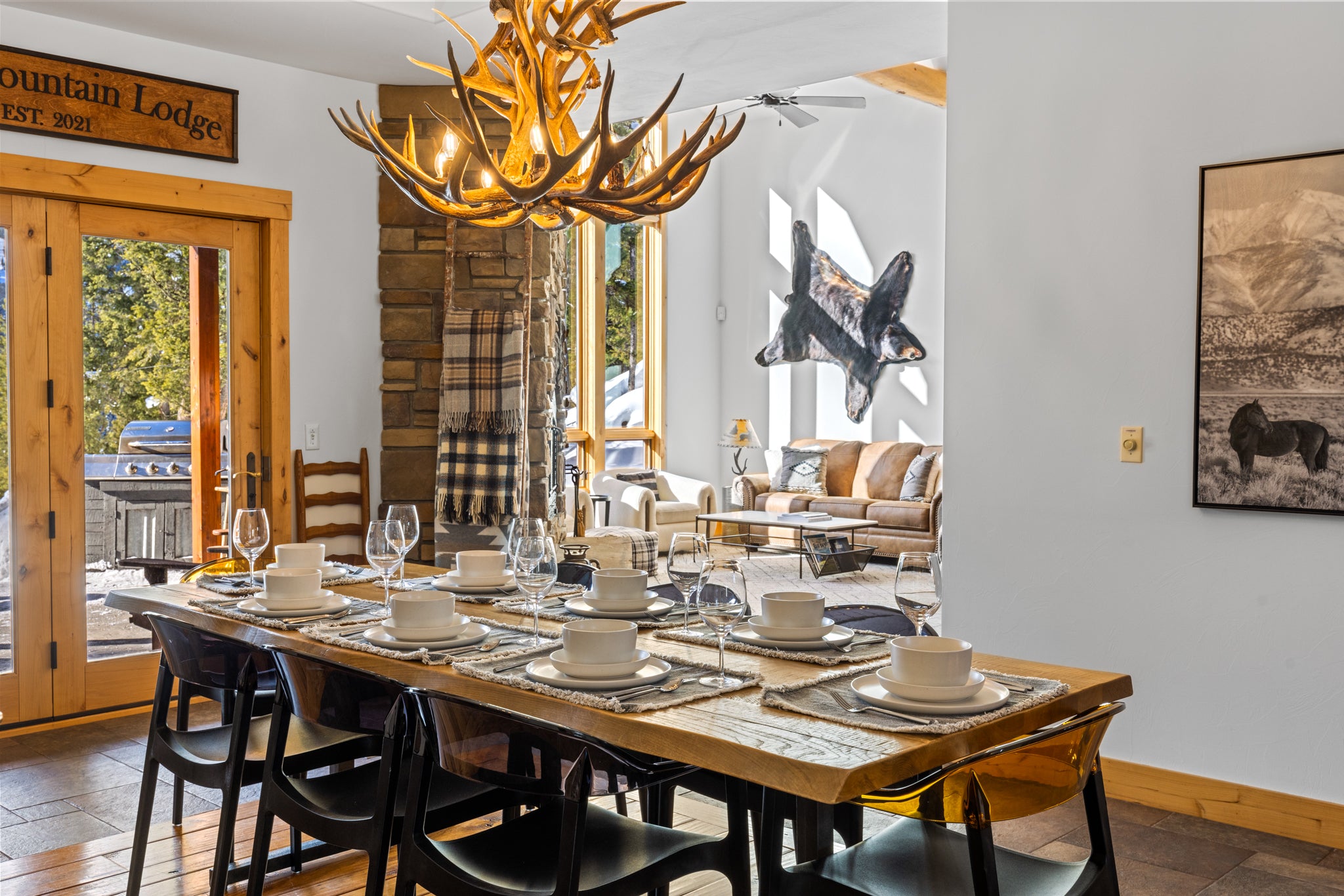 Rustic dining area with table settings for eight beneath an antler chandelier in Big Sky, Montana