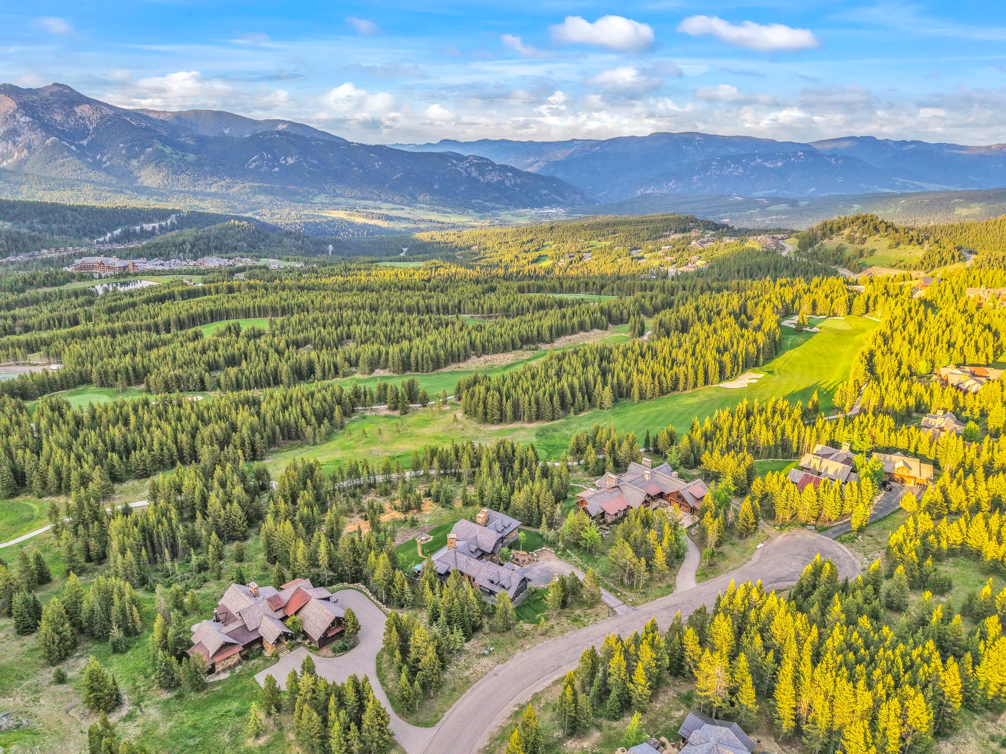 Aerial view of modern mountain homes nestled in trees near golf course in Spanish Peaks Big Sky, Montana