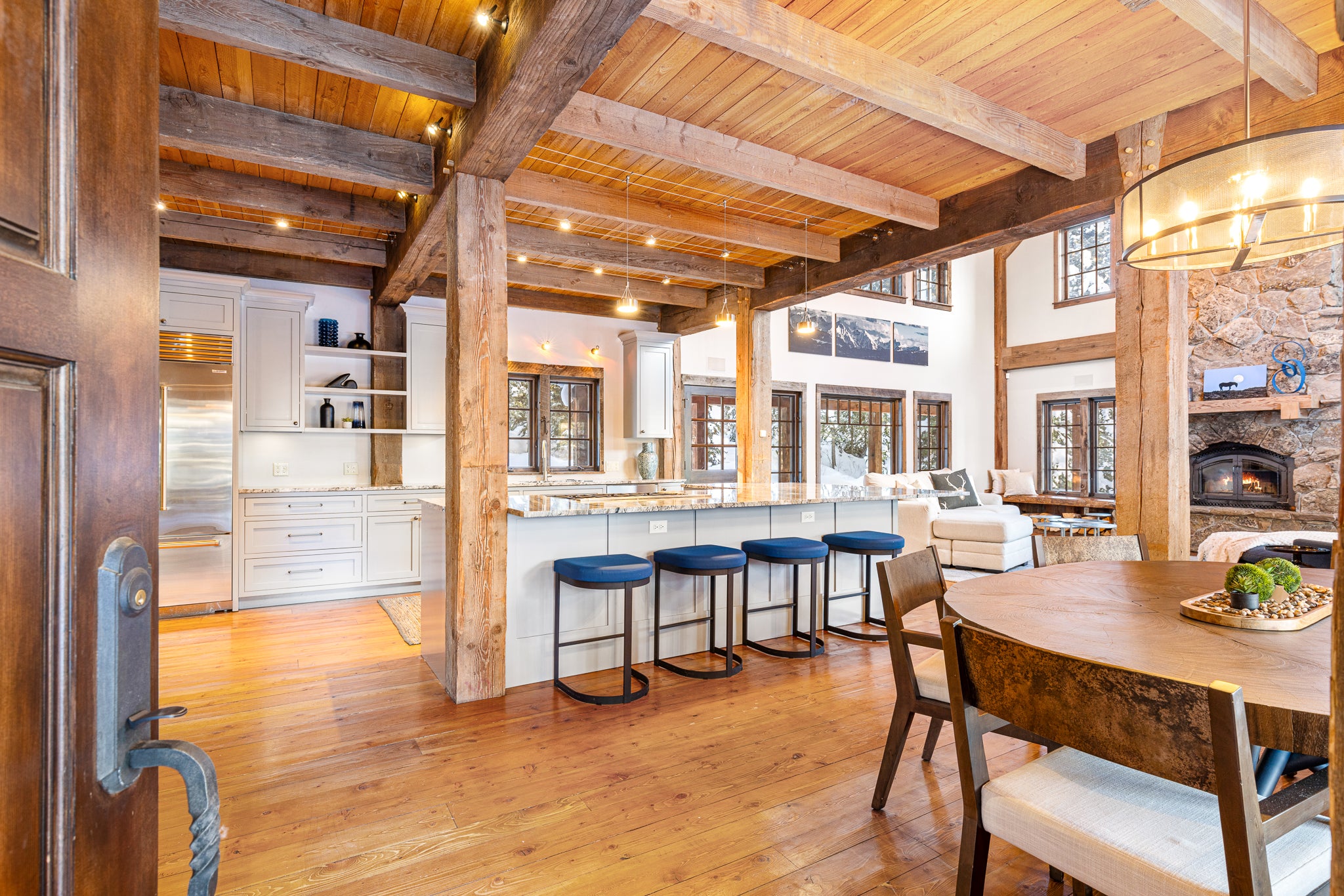 Luxury home entry into kitchen with blue barstools and dining area in Big Sky, Montana captured by Doorstep