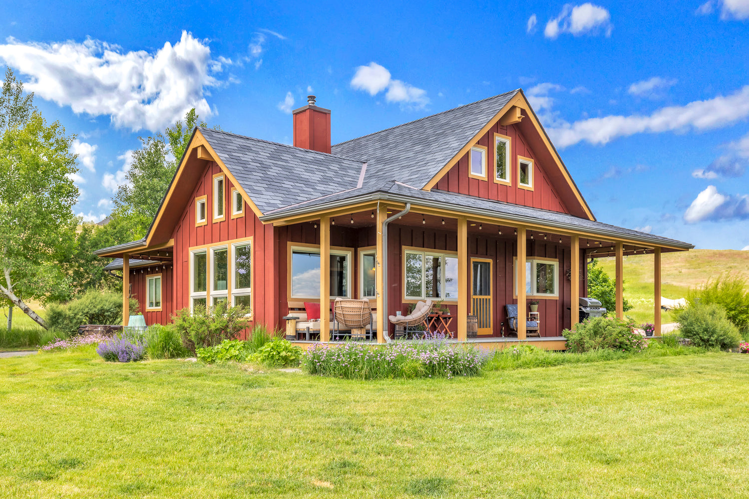 Red house with patio furniture and landscaping in Ennis, Montana